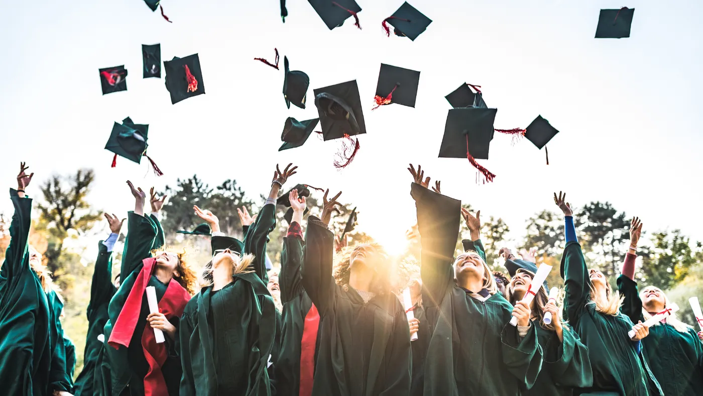 A group of graduates in gowns throwing their caps in the air, celebrating together.