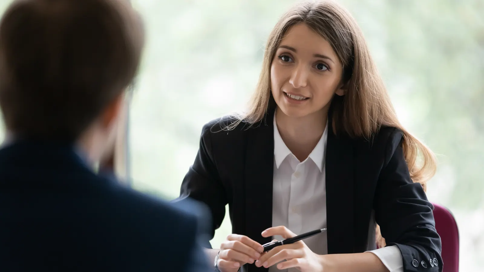 A professional in conversation with a colleague in an office setting.