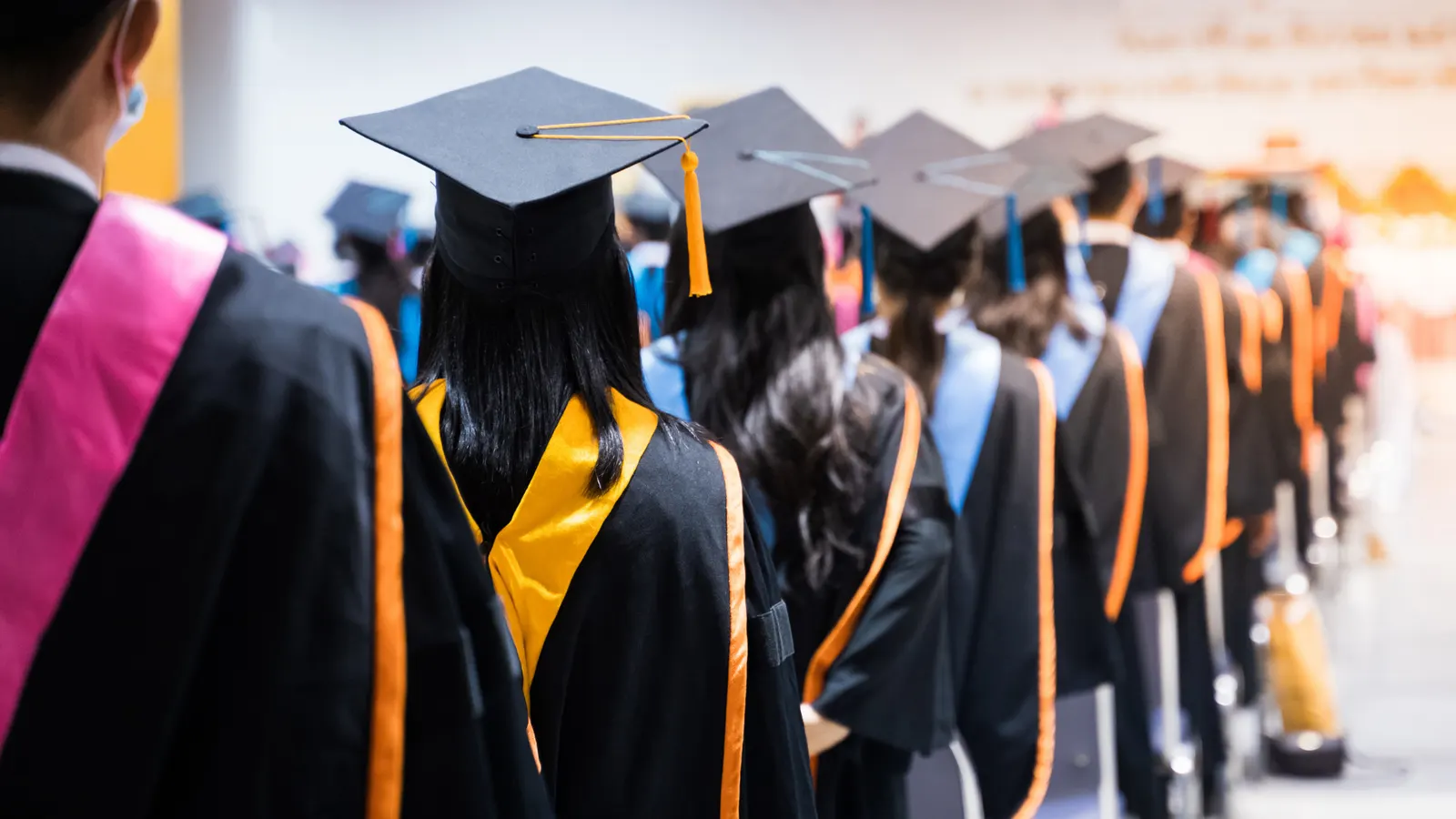A line of graduates in caps and gowns at a graduation ceremony.