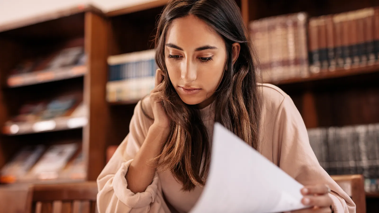 A professional reviewing a document in an office library setting.