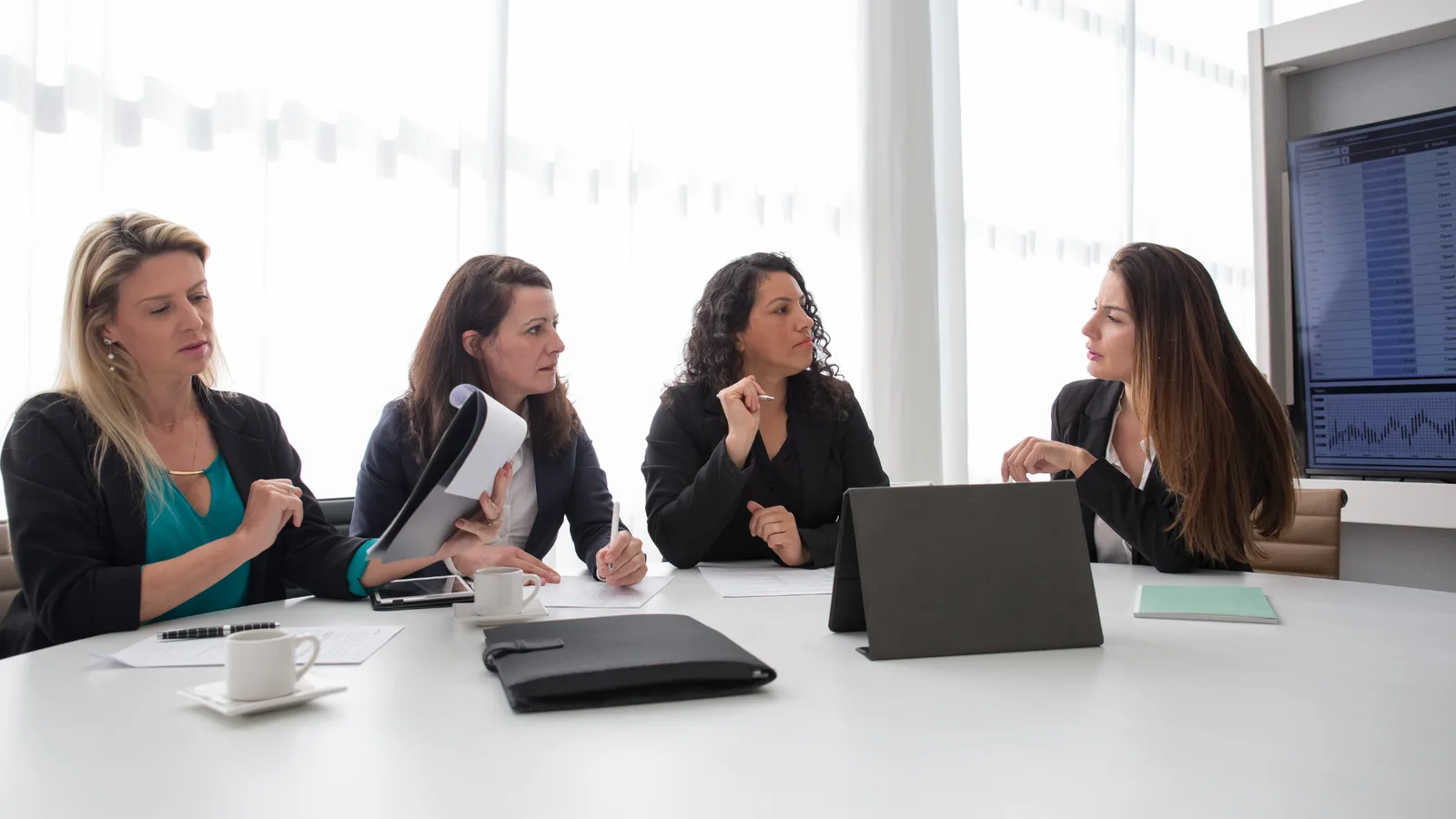 Four professional colleagues in discussion around a table in a bright office.